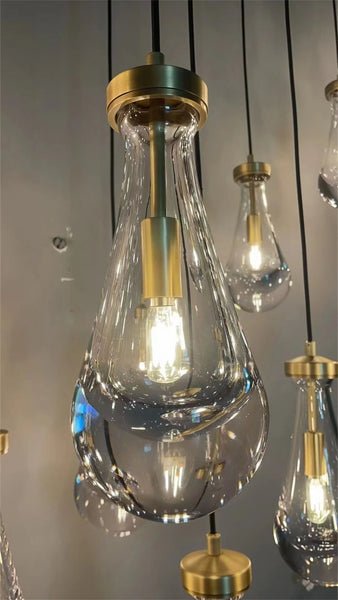 Raine Modern Chandelier with K9 crystal prisms and sleek metal design, perfect for high-ceiling living rooms, foyers, and upscale interiors. Adjustable height, energy-efficient LED compatible.